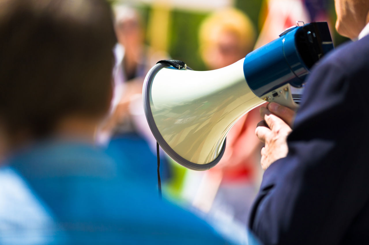 Man holding a megaphone while speaking to strikers holding signs