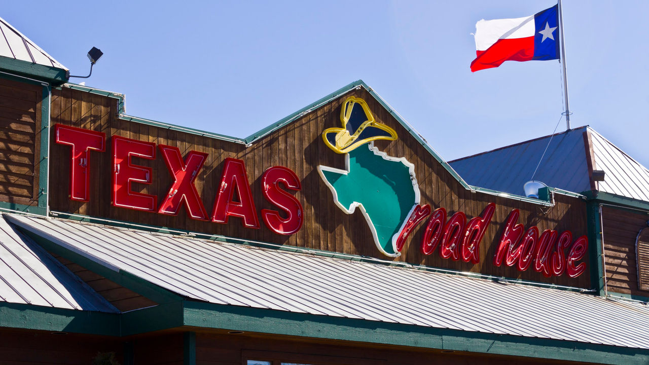 A texas red house sign with a texas flag flying over it.