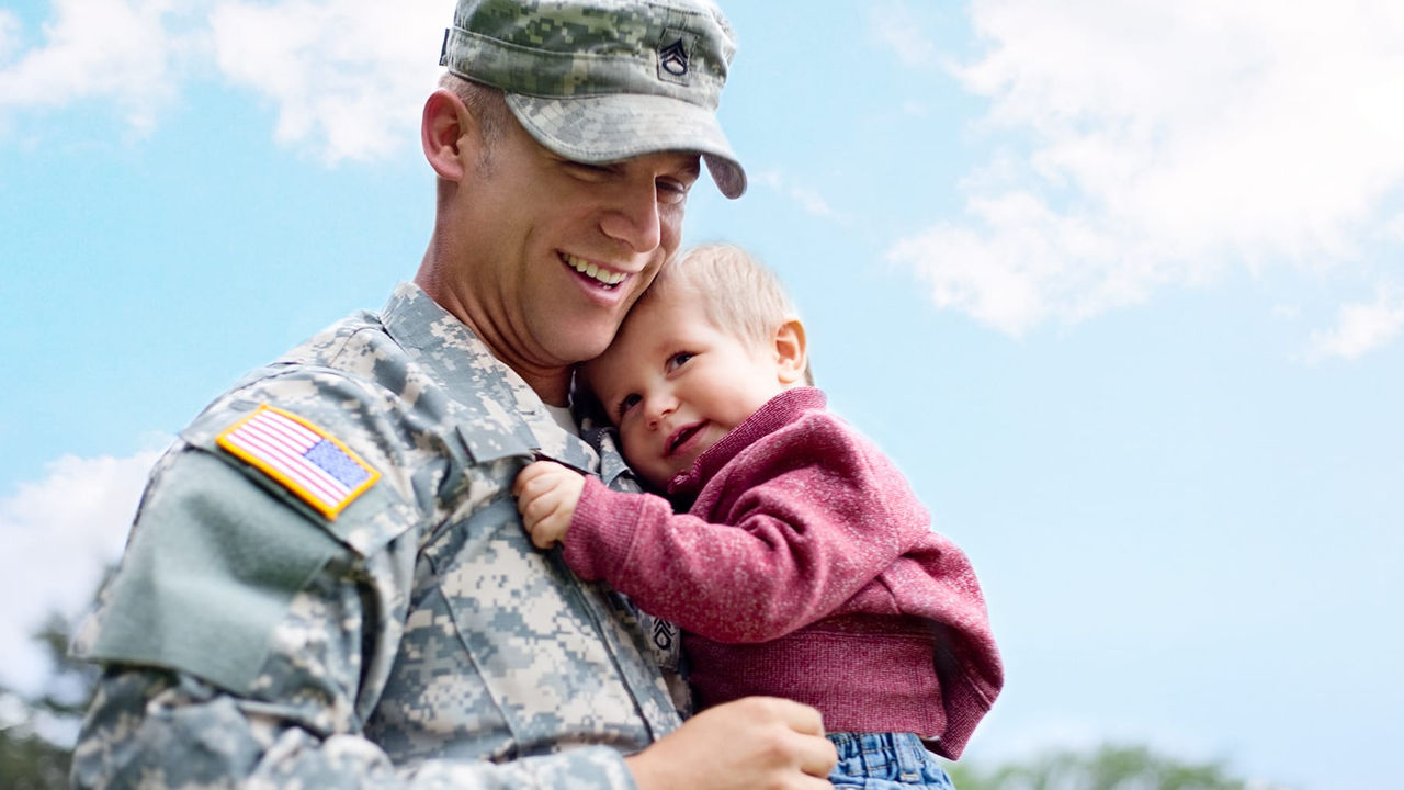 A soldier holding a baby in his arms.