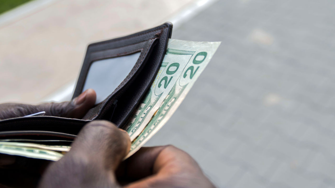 A man is holding a wallet full of money.