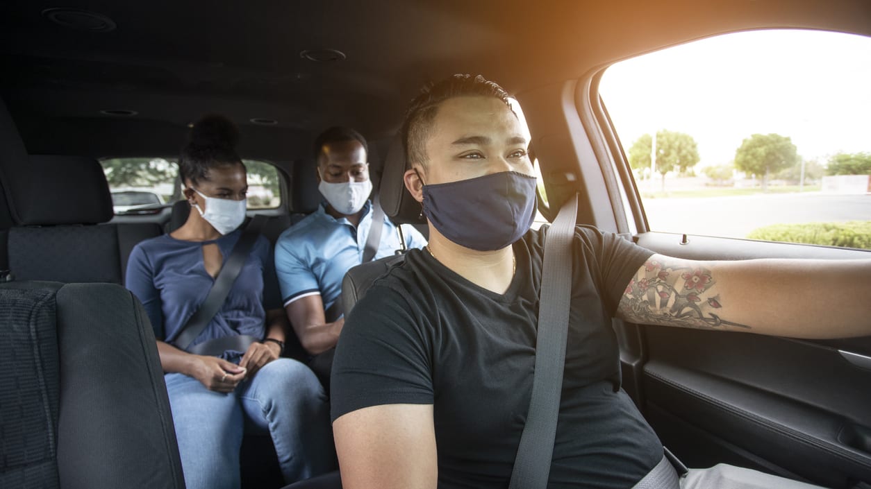 A group of people wearing face masks in a car.