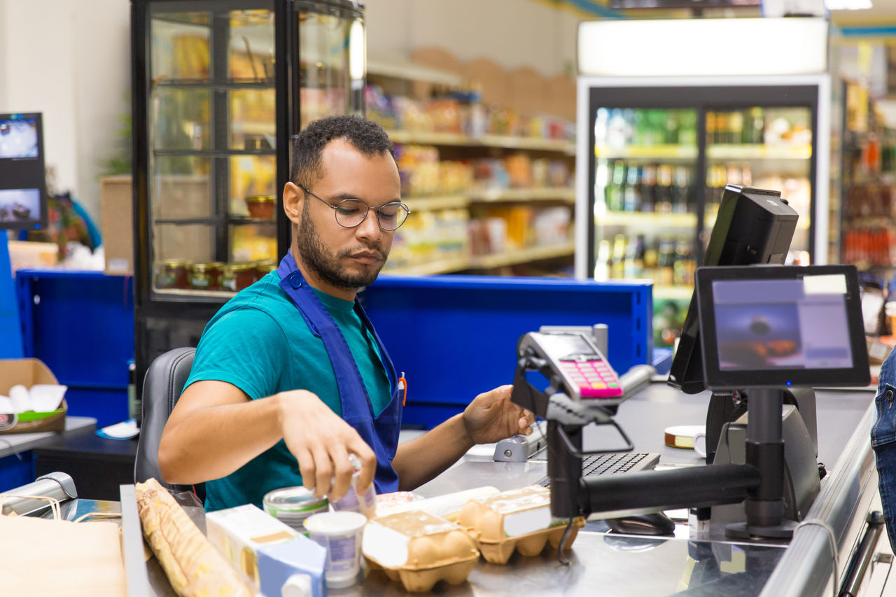 Seated cashier scanning goods at checkout.