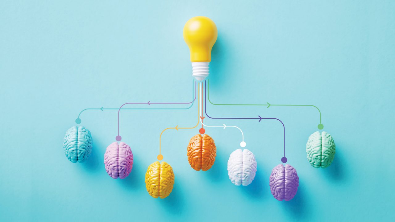 Several colorful brains are connected to a lightbulb.