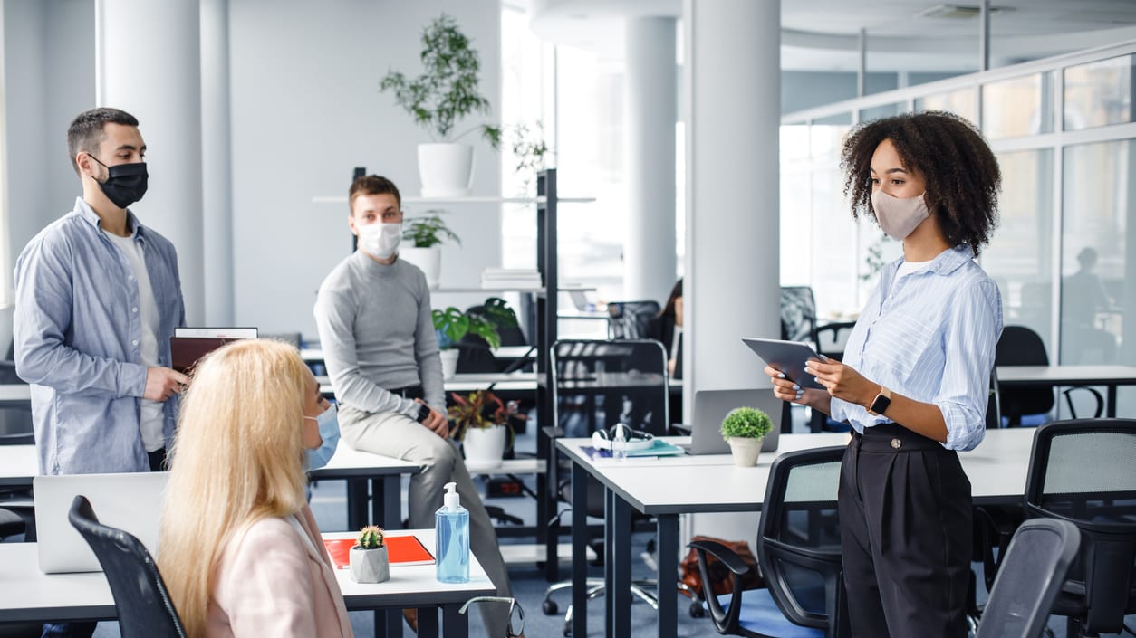 A group of people wearing face masks in an office.