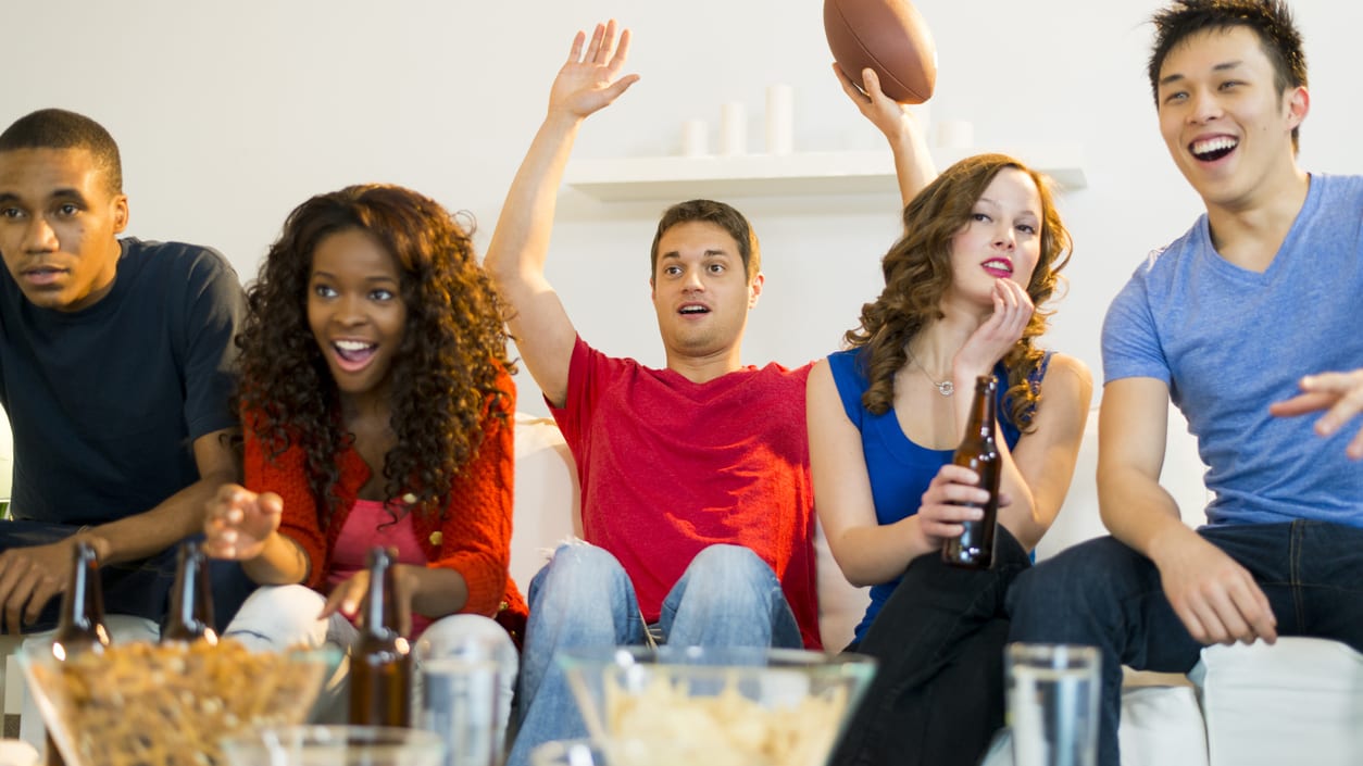 A group of people watching a football game in a living room.