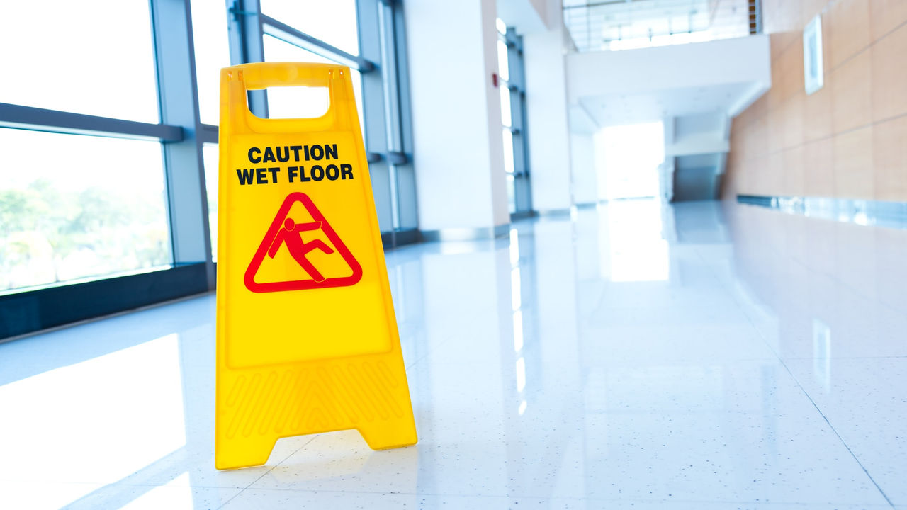 A yellow caution wet floor sign on the floor of an office building.