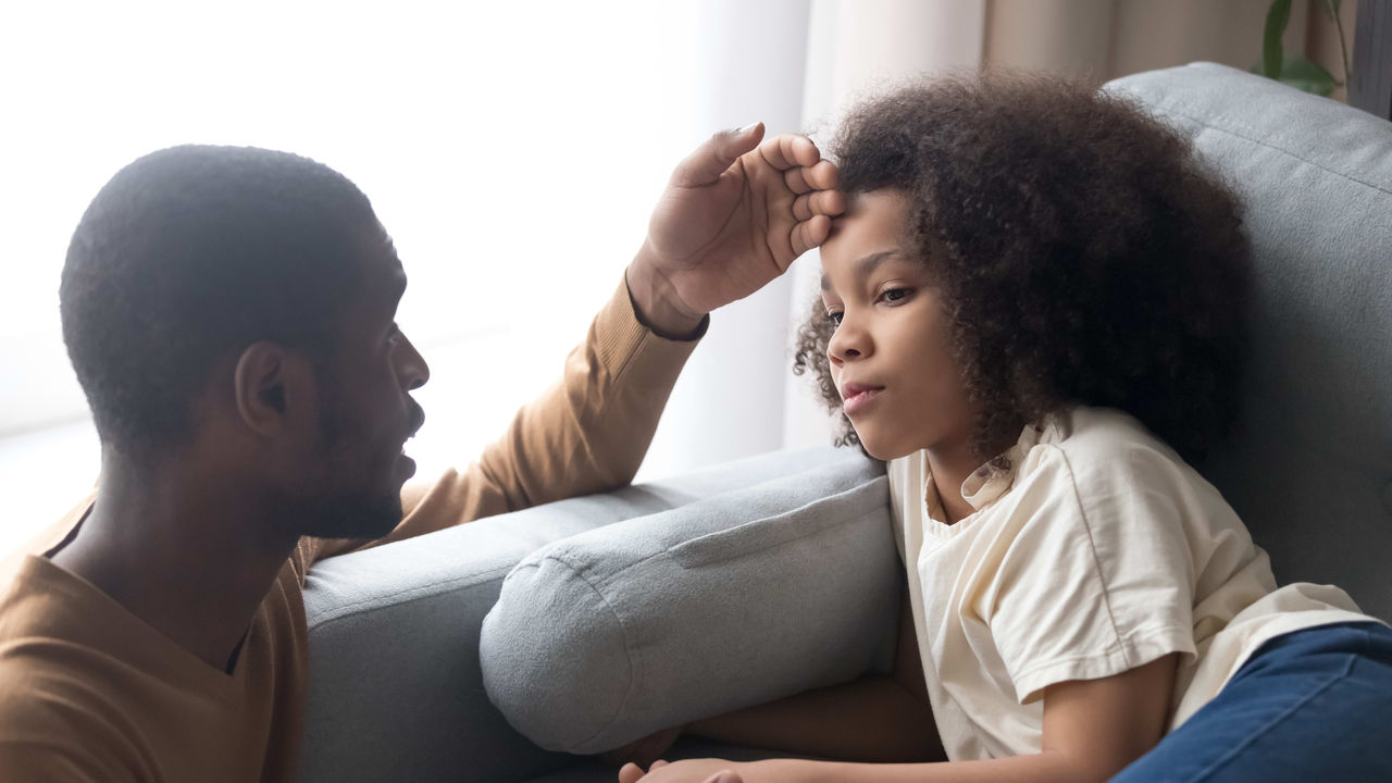 A man is sitting on a couch with his daughter.